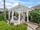 Serene backyard patio with white pergola, comfortable seating, and lush landscaping, creating a private outdoor oasis at 2410 Tamarindo Dr, The Villages, FL 32162