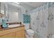 Bathroom featuring vanity with granite top, decorative mirror, and a patterned shower curtain at 257 Winding Cove Ave, Apopka, FL 32703