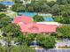 Aerial view of the clubhouse in a wooded community near tennis courts, a parking lot, and a community lake at 26800 Racquet Cir, Leesburg, FL 34748
