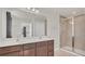 Well-lit bathroom with a double sink vanity, a large mirror, and a glass-enclosed shower at 3054 Hill Point St, Minneola, FL 34715