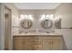 Bathroom featuring dual sinks with round mirrors and wooden cabinets, ample counter space, and a clean aesthetic at 341 Ranchwood Dr, Leesburg, FL 34748
