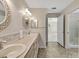 Bathroom with double vanity, tile backsplash, decorative mirrors, with view to bedroom and glass-enclosed shower at 341 Ranchwood Dr, Leesburg, FL 34748