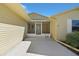A close up of the screened entrance with decorative door and a white bench on the concrete slab at 341 Ranchwood Dr, Leesburg, FL 34748