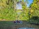 Lush backyard featuring vibrant greenery, a flower bed, and a serene view of the lake beyond at 351 Groveland Rd, Mount Dora, FL 32757
