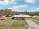 Aerial view of a home with a large yard, storage shed, and long driveway at 3909 Cr 532A, Bushnell, FL 33513