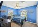 Bright blue bedroom with ceiling fan, carpet flooring, and two windows providing natural light at 3909 Cr 532A, Bushnell, FL 33513