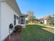 Well-maintained backyard with green lawn, landscaping, and a view of the home's white siding and enclosed patio at 4712 St Andrews Arc, Leesburg, FL 34748