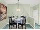 Cozy dining area featuring a glass table with seating for four, complemented by a stylish chandelier and artwork at 4712 St Andrews Arc, Leesburg, FL 34748