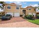 Exterior shot of a beautiful stucco home with a brick driveway and three-car garage, and tasteful landscaping at 5359 Compass Pt, Oxford, FL 34484