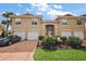 Exterior shot of a beautiful stucco home with a brick driveway and three-car garage, surrounded by landscaping at 5359 Compass Pt, Oxford, FL 34484