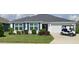 Charming single-story home features a well-manicured lawn, white trim, and a convenient golf cart parked in the driveway at 5978 Conley Ct, The Villages, FL 32163