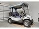 Close-up of a Yamaha golf cart parked in a garage, sitting atop cardboard, highlighting a convenient amenity at 5978 Conley Ct, The Villages, FL 32163