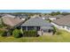 Aerial view of a house showing a screened in back patio under a pergola and luscious green lawn at 6083 Delphina Loop, The Villages, FL 32163