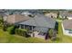 Aerial view of home's backyard screened in patio with pergola surrounded by lush green lawn at 6083 Delphina Loop, The Villages, FL 32163