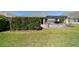 An expansive green lawn leads to a screened patio and outdoor stone grill at 6083 Delphina Loop, The Villages, FL 32163
