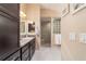 Modern bathroom featuring granite counters, dark cabinetry and a walk-in shower with glass block at 6083 Delphina Loop, The Villages, FL 32163