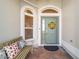 Charming front porch with bench, decorative pillows, colorful door and brick flooring at 6083 Delphina Loop, The Villages, FL 32163