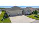 Inviting single-story home showcasing a manicured lawn, brick walkway, and spacious two-car garage at 6083 Delphina Loop, The Villages, FL 32163