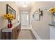 Bright hallway featuring neutral paint, white trim, and tile floors with decorative accents and a wooden accent table at 6083 Delphina Loop, The Villages, FL 32163