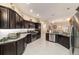 Spacious kitchen with dark wood cabinets, stainless steel appliances, tile floors, and ample counter space for cooking at 6083 Delphina Loop, The Villages, FL 32163