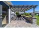 Covered paver patio with overhead pergola overlooking the well-manicured lawn and landscaped backyard at 6083 Delphina Loop, The Villages, FL 32163
