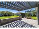 Charming backyard patio area with stone wall and pergola, perfect for outdoor entertaining at 6083 Delphina Loop, The Villages, FL 32163