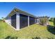 Lush lawn alongside screened back patio under a pergola with decorative trellis at 6083 Delphina Loop, The Villages, FL 32163