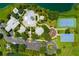 An aerial view shows community amenities like a pool, sports courts, and parking area, bordered by lush greenery at 724 Barefoot Bay Loop, Groveland, FL 34736