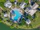 Aerial shot of a community pool with a slide, surrounded by lush greenery and lounge chairs at 724 Barefoot Bay Loop, Groveland, FL 34736