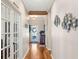 Bright hallway with hardwood floors, decorative fish wall art, leading to a white decorative front door at 724 Barefoot Bay Loop, Groveland, FL 34736