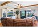 Open living room with a large brown sofa, built-in shelving, and sliding glass doors to an outdoor pool area at 724 Barefoot Bay Loop, Groveland, FL 34736