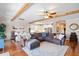 Open concept living area with hardwood floors, exposed wood beams, a large sectional couch, and a dining area at 724 Barefoot Bay Loop, Groveland, FL 34736