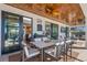 Covered patio featuring a dining table, television, ceiling fan, and sliding glass doors to the interior at 724 Barefoot Bay Loop, Groveland, FL 34736