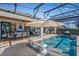 Inviting screened-in pool area with an umbrella, outdoor dining, and luxurious lounge seating at 724 Barefoot Bay Loop, Groveland, FL 34736