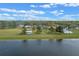 Aerial view of a home near a lake, showcasing an expansive green lawn and outbuildings under a partly cloudy sky at 7729 Lake Andrea Cir, Mount Dora, FL 32757