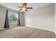 Bright bedroom featuring a ceiling fan, tan carpet, and a window offering a pleasant view at 7729 Lake Andrea Cir, Mount Dora, FL 32757