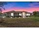 Beautiful single-story home with a well-maintained lawn and mature landscaping, set against a vibrant twilight sky at 7729 Lake Andrea Cir, Mount Dora, FL 32757