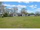 The home's back exterior shows a screen-enclosed porch, windows, a large backyard, and mature trees beyond at 7729 Lake Andrea Cir, Mount Dora, FL 32757