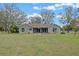 Back exterior view featuring a screen enclosed porch with large windows overlooking a spacious grassy backyard at 7729 Lake Andrea Cir, Mount Dora, FL 32757