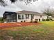 Wide view of a home's rear elevation, including a screened in porch, tidy yard, and manicured bushes at 9113 Sw 91St Court Rd, Ocala, FL 34481
