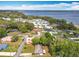 An aerial view of a neighborhood with homes, tree canopies, streets, and a lake on the horizon at 1108 Cedar St, Leesburg, FL 34748