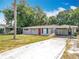 Exterior view showcasing the well-maintained home, long driveway, mature trees, and convenient carport at 1108 Cedar St, Leesburg, FL 34748