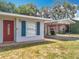 Close-up of the front entrance with a red door, decorative shutters, and covered carport access at 1108 Cedar St, Leesburg, FL 34748