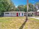 Charming single-story home featuring a bright red front door, manicured lawn, and covered carport at 1108 Cedar St, Leesburg, FL 34748