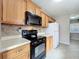 Traditional kitchen featuring wood cabinets, tile floors, and black appliances at 1108 Cedar St, Leesburg, FL 34748