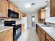 Traditional kitchen featuring wood cabinets, tile floors, and black appliances at 1108 Cedar St, Leesburg, FL 34748