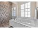 Bright bathroom showcasing soaking tub with tiled surround and glass-enclosed shower with chevron tile at 114 Cherry Creek Cir, Winter Springs, FL 32708