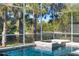 A screened-in pool with an attached hot tub and views of the trees beyond the screen enclosure at 114 Cherry Creek Cir, Winter Springs, FL 32708