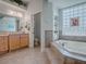 Bright bathroom with a soaking tub, tile surround, and natural light from glass block window at 1239 Russell Loop, The Villages, FL 32162