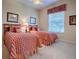 Bright bedroom with two twin beds featuring red and white bedding and a ceiling fan at 1239 Russell Loop, The Villages, FL 32162